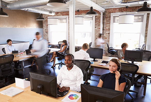 Open-plan office with people working at desks and on computers.