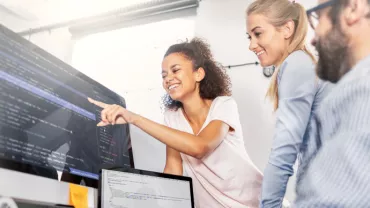 Group collaborating on code project at computers in office.